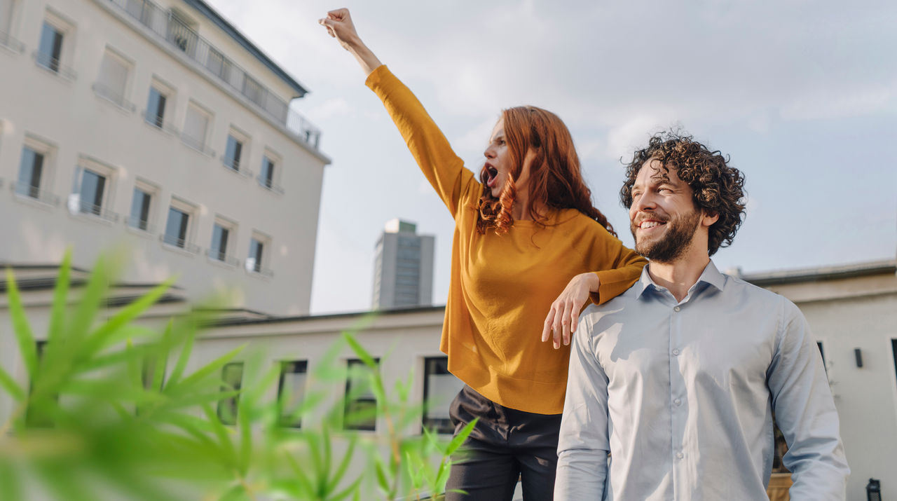 Woman with colleague on roof terrace clenching fist