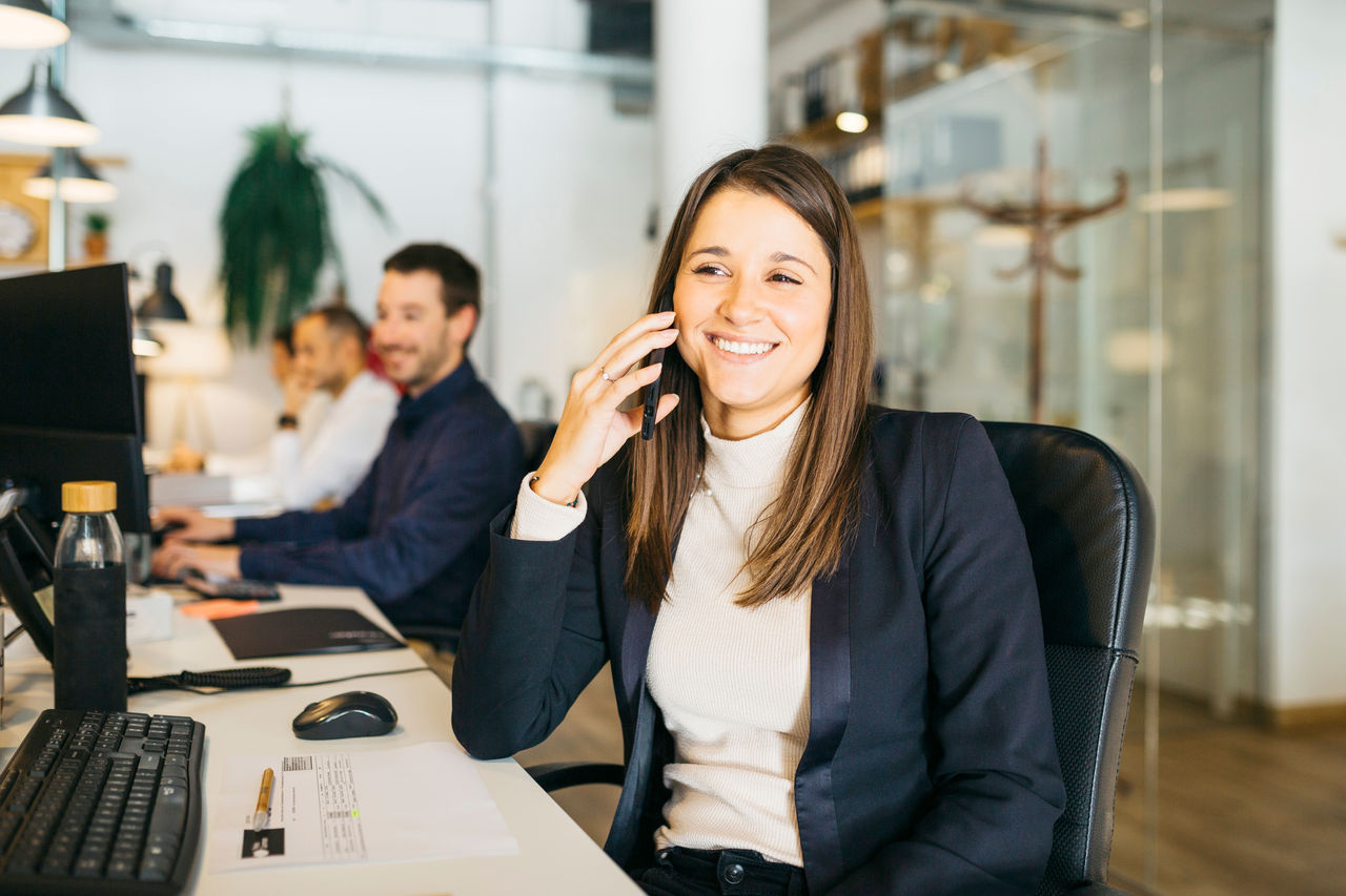 Smiling young woman talking on a smartphone in a office; Shutterstock ID 2087235706; purchase_order: TES 2140-001 ; job: Lizensierung Bildmaterial fuÌ r Dorothea Heller 13-12-2021; client: Techem / faust & auge; other: 