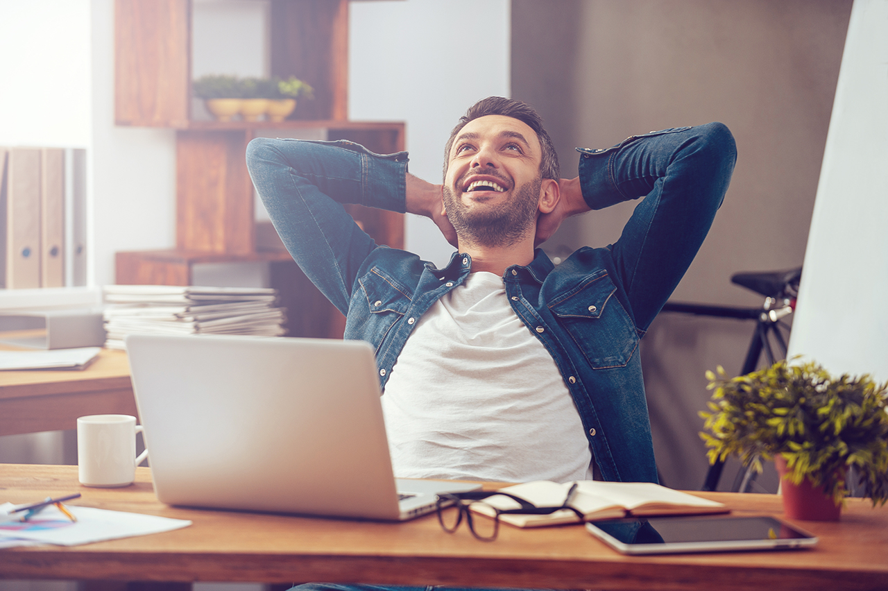 Satisfied with work done. Happy young man working on laptop while sitting at his working place in office; Shutterstock ID 345950657