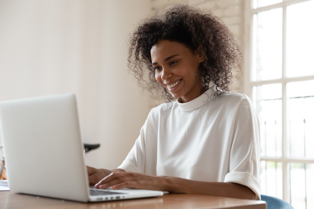 Frau am Laptop, schreiben, lächeln