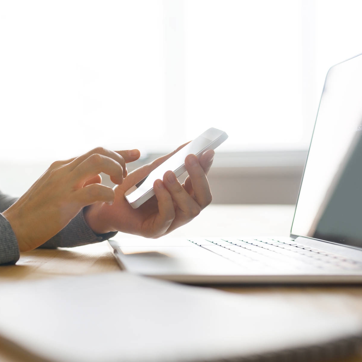 Person using laptop and phone for work, clean simple close up; Shutterstock ID 556094341