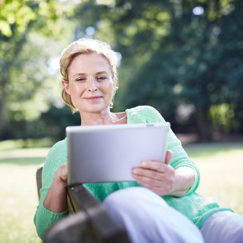 Frau sitzt im Garten und prüft auf dem Laptop die Vermieter Checkliste