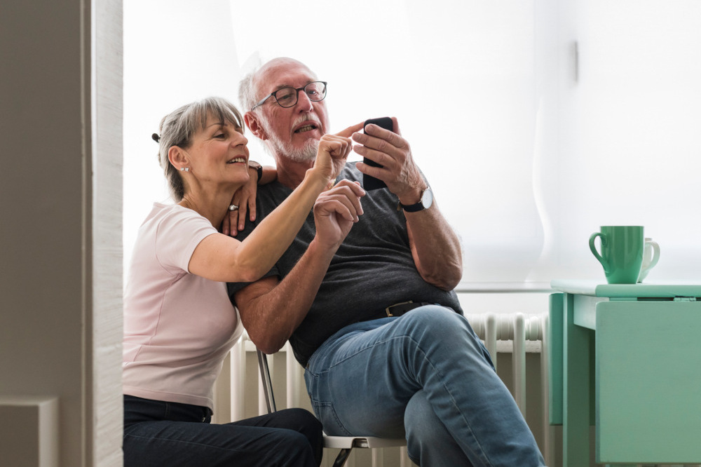 Senior couple using a phone at home.