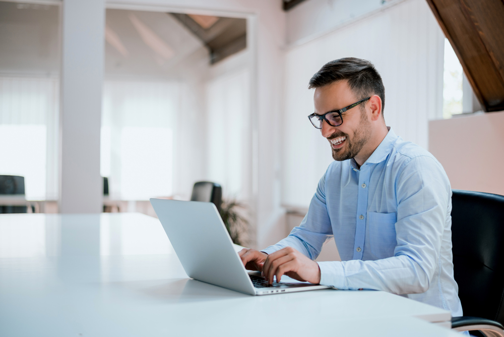 Portrait of young man sitting at his desk in the office; Shutterstock ID 648506098