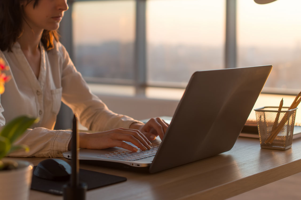 Side view photo of a female programmer using laptop, working, typing, surfing the internet at workplace. ; Shutterstock ID 409299172