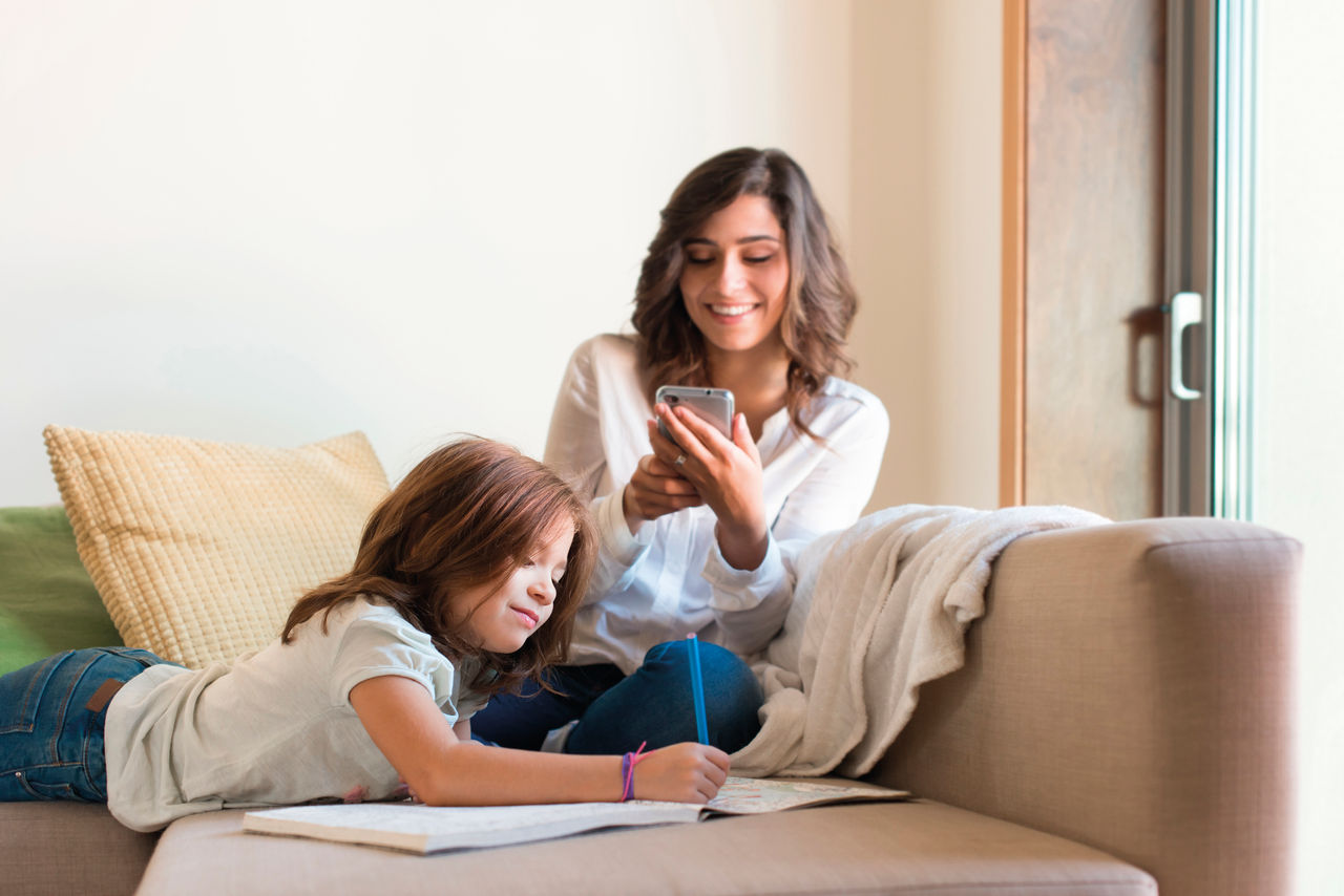 Little girl painting in the living room while mom is on internet; Shutterstock ID 393706300