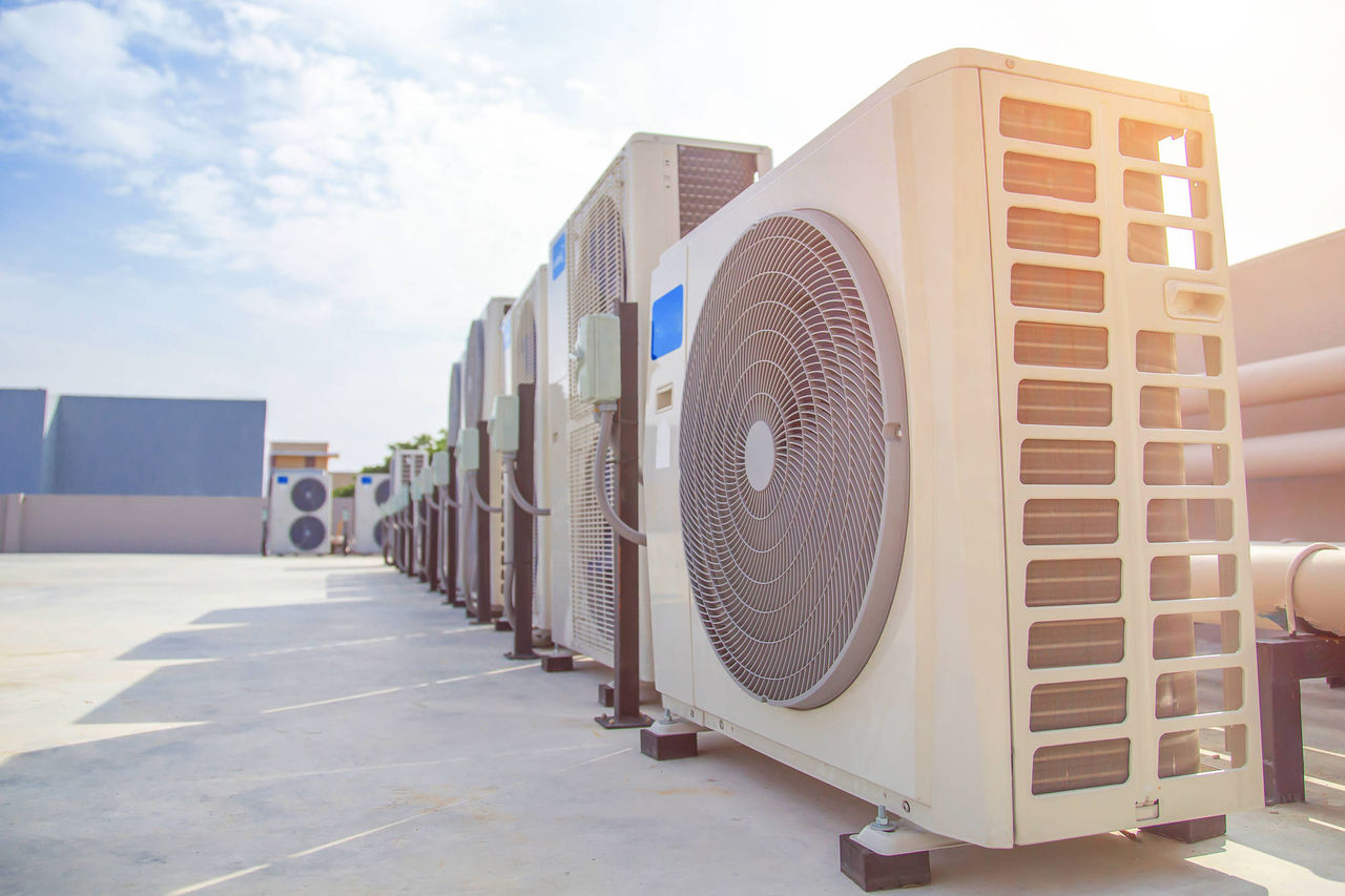 Air conditioning (HVAC) on the roof of an industrial building with blue sky and clouds.