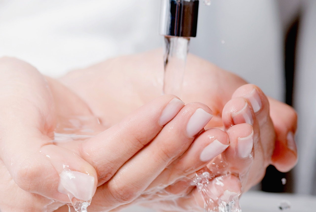 Hände ineinander gelegt unter fließendem Wasser aus dem Wasserhahn. 